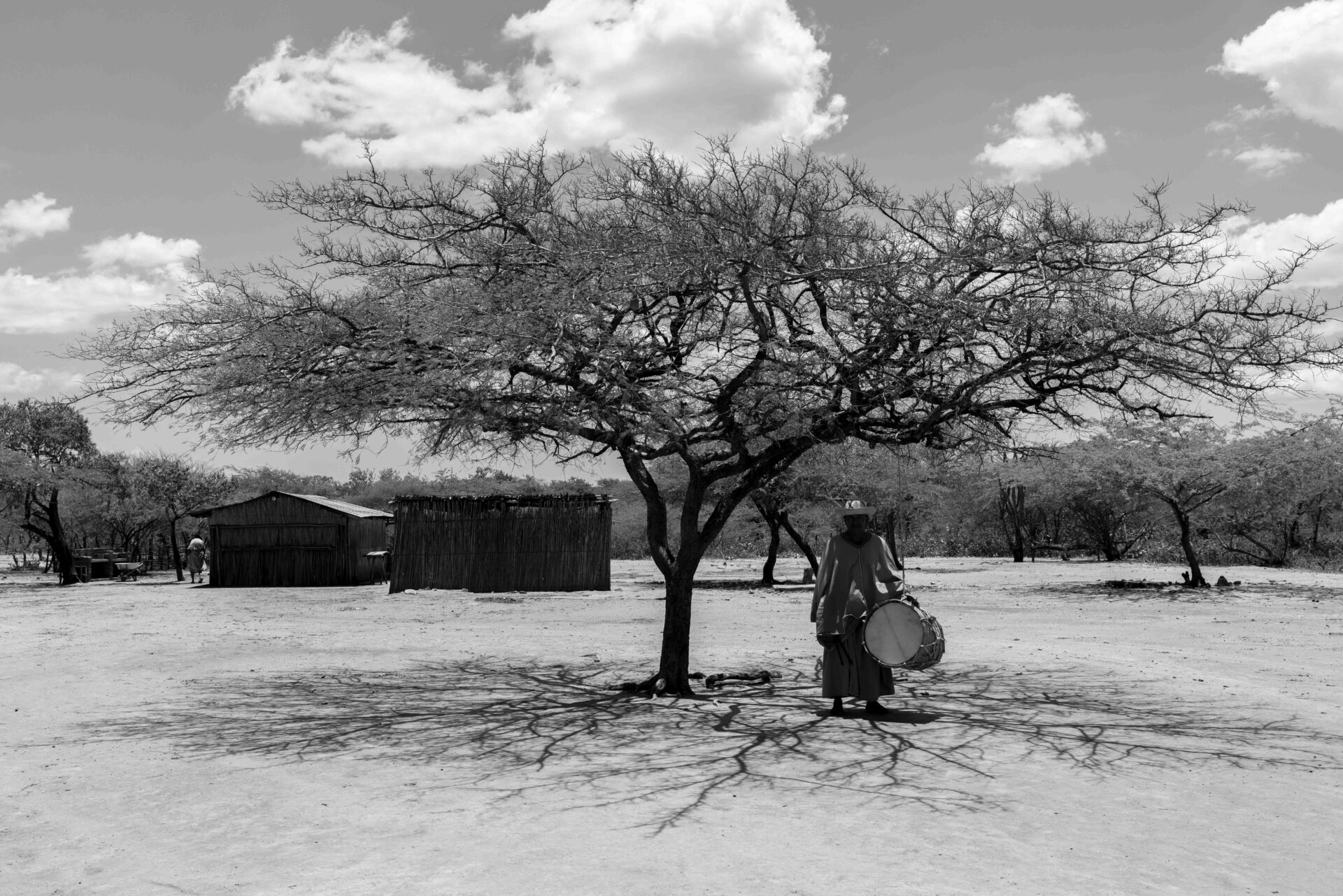 Alejandro Pinedo, a member of the Wayuu indigenous community, plays the drum under a tree to welcome the representatives of Grupo Energia Bogota (GEB) to the "ranchería" Pirruwaitamana in La Guajira department, Colombia, on Friday, August 11, 2023. Photographer: Fernanda Pineda/Bloomberg.