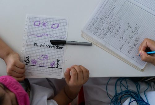 Mientras Claudia Vallejo de 26 años y perteneciente a la etnia indigena Arahuaca ubicada en la Sierra Nevada de Santa Marta y sus estribaciones realiza ejercicios de calculo necesarios para su carrera como estadista su hija Dwiney de 6 años sentada a su lado al interior de la bibliteca colorea y dibuja.